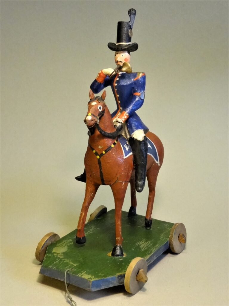 1 Ziehspielzeug Postillion, Hersteller: Familie Otto, Arnsfeld um 1860, Figur wurde freigelegt, Pferdeschweif, Posthorn und Hutfeder wurden ergänzt, farbliche Retusche.