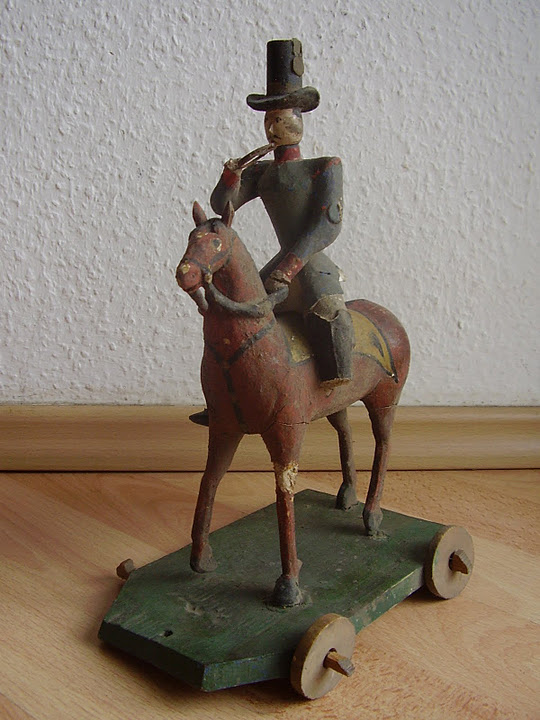 1a Ziehspielzeug Postillion, Hersteller: Familie Otto, Arnsfeld um 1860, Figur wurde freigelegt, Pferdeschweif, Posthorn und Hutfeder wurden ergänzt, farbliche Retusche.